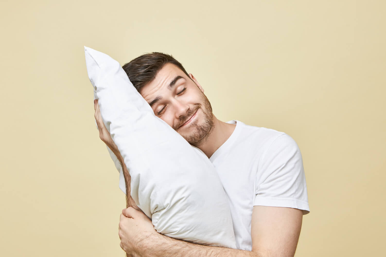 horizontal-image-handsome-cute-young-man-with-bristle-posing-with-head-white-soft-pillow-sleeping-peacefully-smiling-seeling-good-dream-attractive-guy-napping-after-hard-working-day