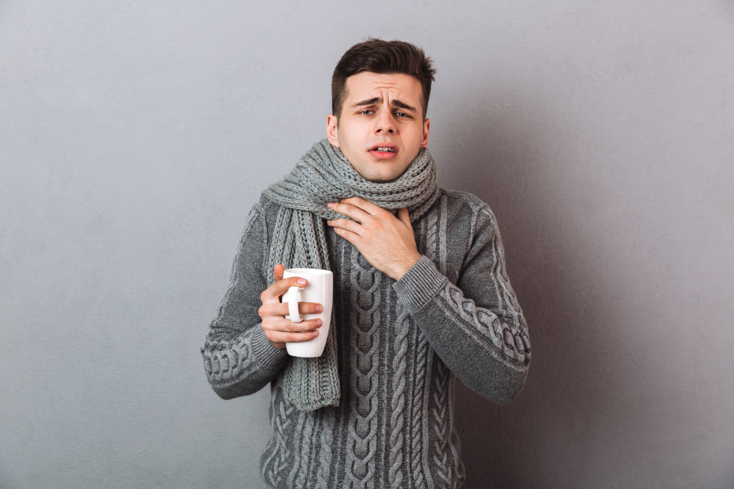 sick-man-sweater-scarf-having-sore-throat-while-holding-cup-tea