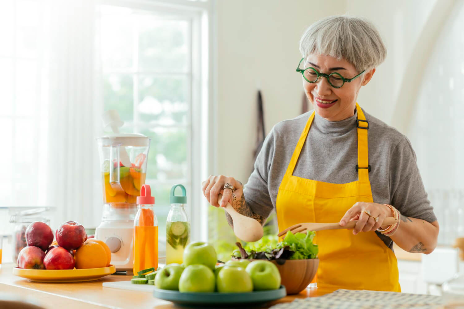 mature-smiling-tattoo-woman-eating-salad-fruits-vegetables-attractive-mature-woman-with-fresh-green-fruit-salad-home-senior-woman-apron-standing-kitchen-counter-relaxing-house